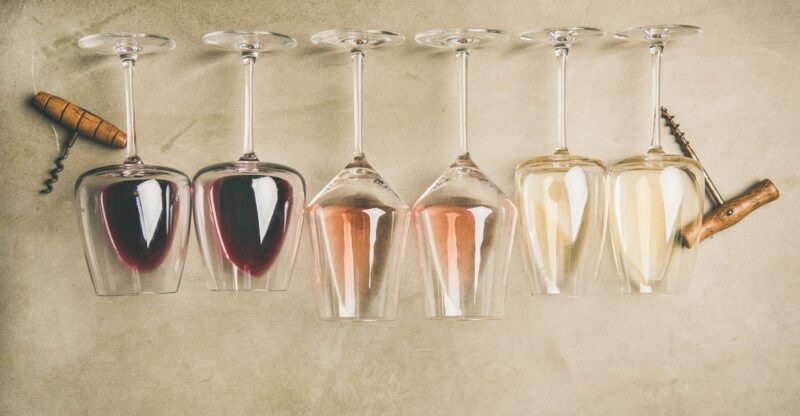 different wines in glasses in row and corkscrews, top view